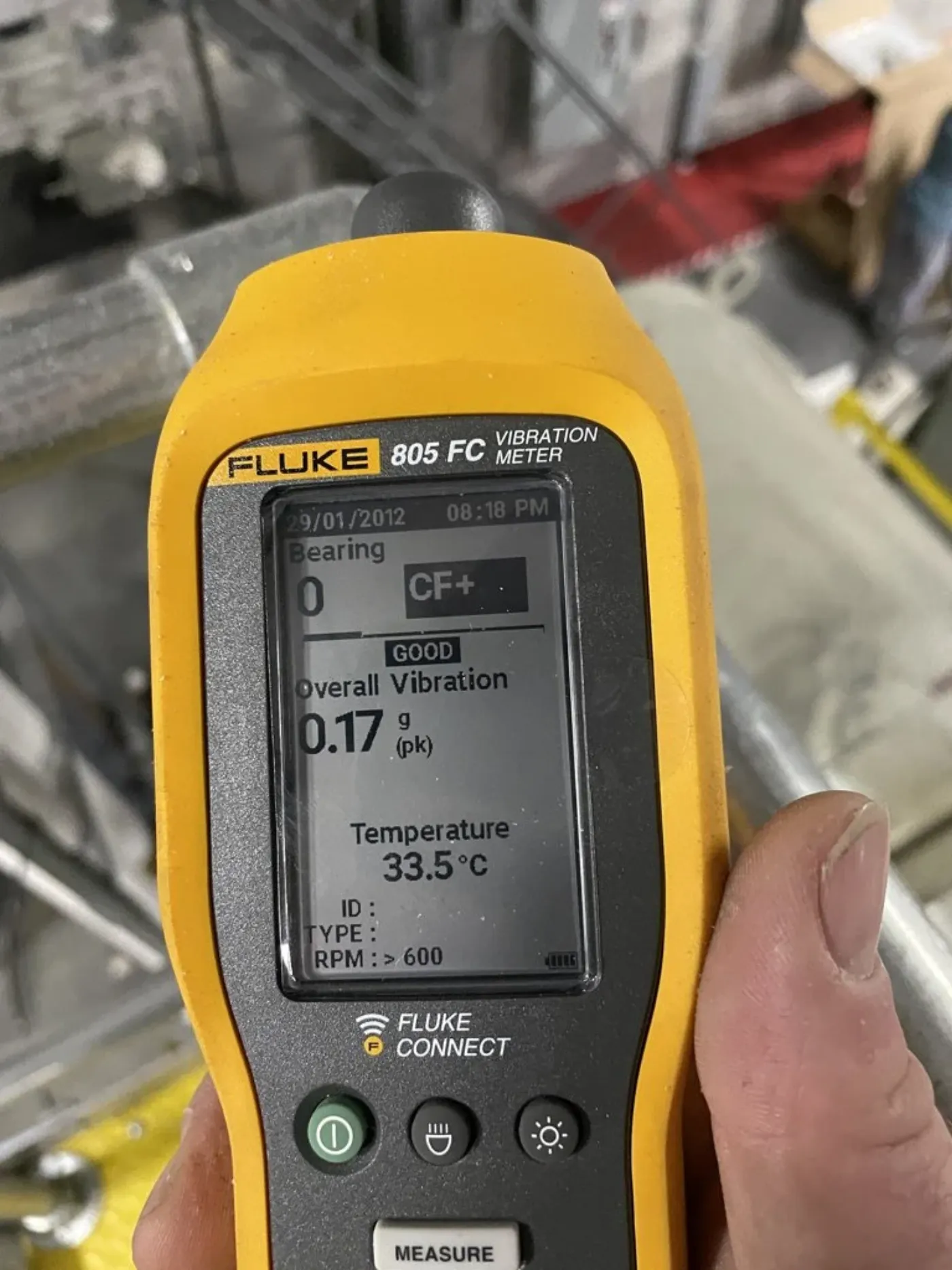 Fluke 805 vibration meter reading a bearing measurement on running equipment